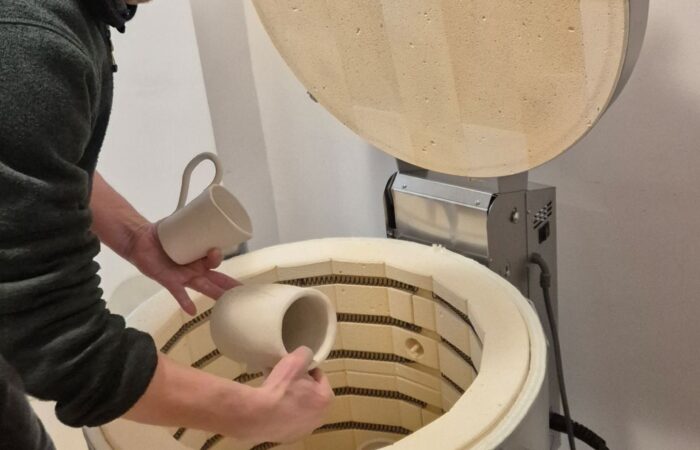 Wykładowca wyciąga z pieca wypalone przedmioty ceramiczne